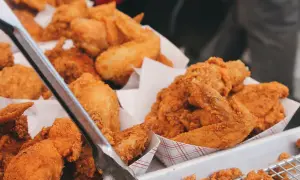 Unas bandejas llenas de crujiente pollo frito, listo para ser servido. Las piezas doradas y sabrosas invitan a disfrutar de este clásico.