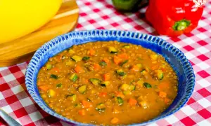 Un plato azul con un guiso de lentejas, zanahoria y calabacín. Una idea deliciosa de como hacer lentejas.