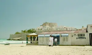 El chiringuito de Pepe, un restaurante playero con vistas a un pueblo blanco y un castillo.