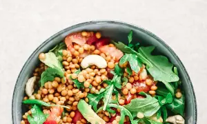 Deliciosa ensalada de lentejas con aguacate, tomate y rúcula, coronada con anacardos. Un plato fresco y nutritivo.