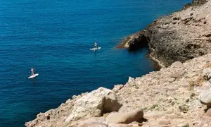 Dos personas hacen paddle surf en aguas turquesas, una actividad genial que ver en Alcossebre con niños.