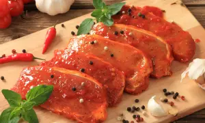 Filetes de lomo adobado listos para cocinar, con pimientos rojos, ajo y hierbas frescas.