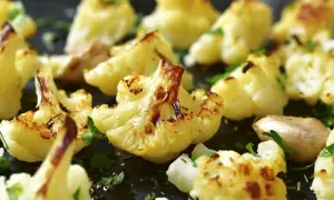 Coliflor al ajillo, dorada y tierna, con trozos de ajo y perejil fresco espolvoreado. Un plato sencillo y delicioso.
