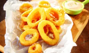Crujientes calamares a la andaluza, dorados y listos para mojar en una cremosa salsa.
