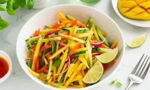 Ensalada de mango vibrante con pepino, zanahoria, cebolla morada y pimientos, aderezada con lima.