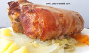 Codillo de cerdo asado, jugoso y dorado, servido con patatas, cebolla y zanahorias. ¡Un manjar!