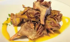 Deliciosas alcachofas fritas crujientes, servidas con una salsa dorada y perejil picado.