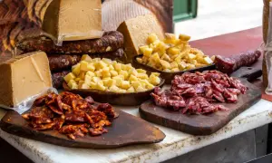 Tabla con quesos y embutidos, incluyendo un delicioso tartar de salchichón, listo para degustar.