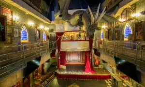 Dragón suspendido sobre un escenario teatral en el magic museum Peñíscola. Ventanas góticas y pósters de ilusionismo adornan las paredes.