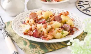 Deliciosa ensalada de coliflor con uvas rojas, prosciutto crujiente y avellanas tostadas. Un plato fresco y lleno de sabor.