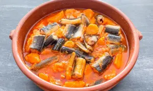 Un cuenco de barro con un delicioso all i pebre, un guiso tradicional de anguilas y patatas en salsa roja.