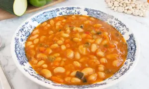 Plato de alubias blancas de bote con verduras en salsa de tomate. Un guiso casero y nutritivo, perfecto para tus recetas.