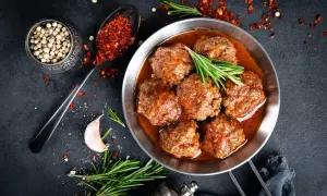 Sabrosas albóndigas con tomate, servidas en sartén, con romero, ajo y especias.