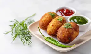 Croquetas de puchero doradas y crujientes, servidas con kétchup, salsa verde y guindillas.
