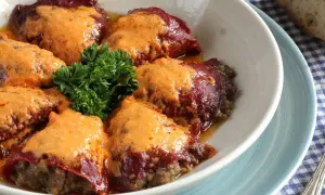 Pimientos rellenos de carne de la abuela, cubiertos con una cremosa salsa y decorados con perejil fresco. Un plato casero que evoca recuerdos.