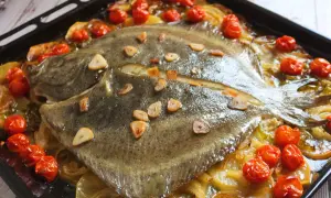 Rodaballo al horno con tomates cherry y láminas de ajo. Un plato delicioso y fácil de preparar.