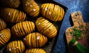 Patatas asadas doradas y crujientes, cortadas en láminas finas y espolvoreadas con sal marina y cebollino fresco. ¡Un placer para la vista y el paladar!