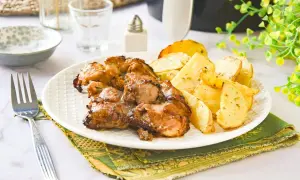 Jugosos contramuslos de pollo dorados con patatas asadas, un plato perfecto para disfrutar.