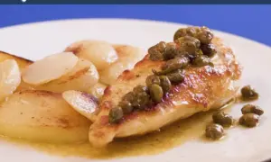 Pechuga de pollo dorada con alcaparras, servida con patatas salteadas en una salsa dorada.