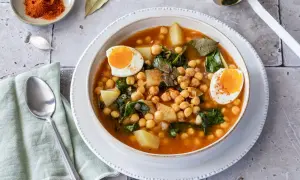 Un reconfortante plato de garbanzos con espinacas, patatas y huevos duros, espolvoreado con pimentón.