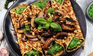 Crepes salados rellenos de aguacate y champiñones salteados, decorados con piñones y albahaca fresca.