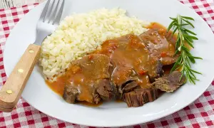 Deliciosa lengua en salsa con arroz blanco y una ramita de romero. Un plato reconfortante listo para disfrutar.