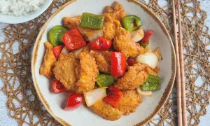 Saborea este delicioso pollo agridulce, crujiente por fuera y tierno por dentro, con pimientos y cebolla. ¡Un festín para tus sentidos!