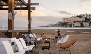 Una mujer disfruta de la tarde en la playa sur Peñíscola, sentada en una silla de diseño frente al mar.