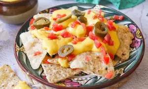 Nachos con queso, cubiertos con jalapeños y tomate picado, listos para disfrutar.
