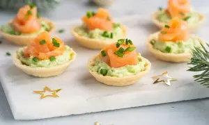 Aperitivos baratos para mucha gente: tartaletas crujientes con aguacate cremoso y salmón ahumado, decoradas con cebollino. ¡Perfectas para fiestas!