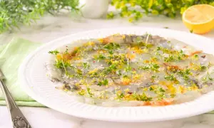 Delicado carpaccio de gambas con hierbas frescas y ralladura de limón, listo para disfrutar.
