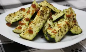 Delicioso calabacín al horno, cortado en bastones y cubierto con queso derretido y hierbas aromáticas.