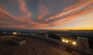 Atardecer espectacular sobre el mar y la costa. Un mirador perfecto para ver qué ver en Alcossebre, con un banco y luces que invitan a contemplar.