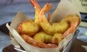 Crujientes gambas a la gabardina doradas y jugosas, servidas en una cesta metálica con papel de estraza.