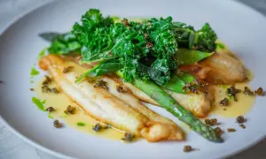 Filetes de bacalao en salsa verde, acompañados de espárragos y kale crujiente.