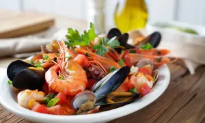 Un delicioso salpicón de marisco con gambas, mejillones, pulpo y almejas, adornado con tomate y perejil.