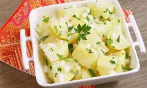 Papas aliñas recién preparadas, con trocitos de cebolla y perejil fresco, listas para disfrutar.