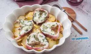 Rodajas de pescado rosado al horno con patatas, cubiertas de hierbas frescas.