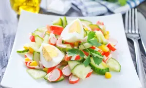Deliciosa ensalada de cangrejo con pepino, huevo cocido y maíz, decorada con perejil fresco.