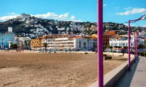 Playa de Peñíscola con el paseo marítimo y edificios blancos escalonados en la ladera de una montaña.