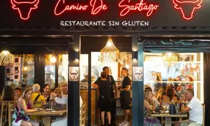Restaurante "Camino de Santiago" en Peñíscola, con letrero de neón y comensales disfrutando de una comida.