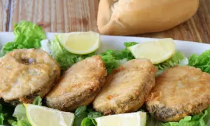 Crujiente merluza a la romana, servida sobre lechuga fresca y gajos de limón. Un plato perfecto para disfrutar.
