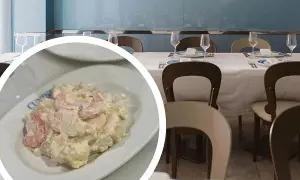 Deliciosa ensaladilla de gambas cremosa, servida en un plato blanco, lista para disfrutar en un restaurante con mesas puestas.