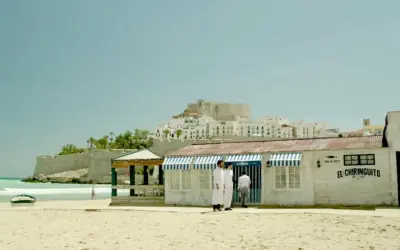 El chiringuito de Pepe, un restaurante playero con vistas a un pueblo blanco y un castillo.