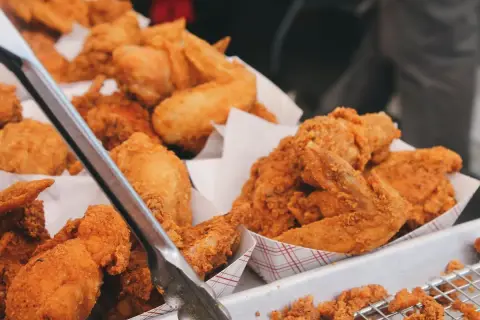Unas bandejas llenas de crujiente pollo frito, listo para ser servido. Las piezas doradas y sabrosas invitan a disfrutar de este clásico.