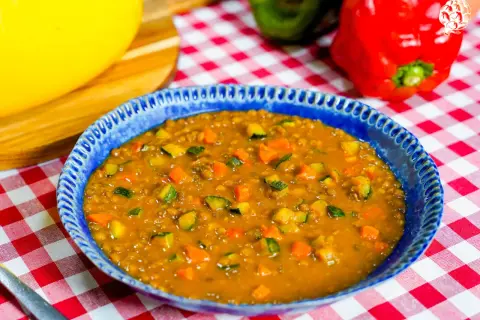 Un plato azul con un guiso de lentejas, zanahoria y calabacín. Una idea deliciosa de como hacer lentejas.