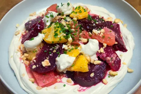 Deliciosa ensalada de remolacha con cítricos, crema y frutos secos picados.