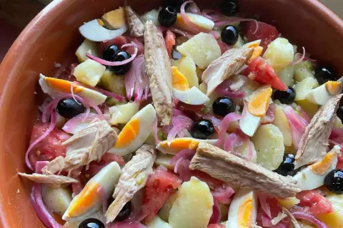 Deliciosa ensalada campera con patatas, huevo duro, atún, aceitunas negras y cebolla morada. ¡Un plato fresco y completo!