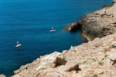 Dos personas hacen paddle surf en aguas turquesas, una actividad genial que ver en Alcossebre con niños.