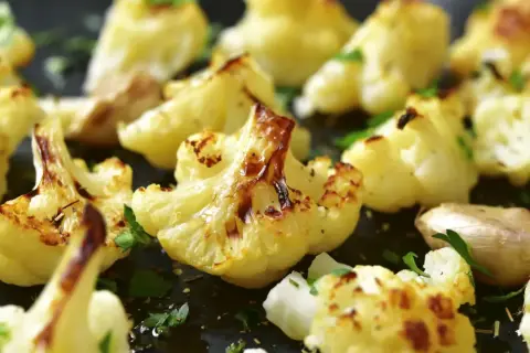 Coliflor al ajillo, dorada y tierna, con trozos de ajo y perejil fresco espolvoreado. Un plato sencillo y delicioso.